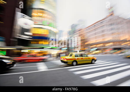 Tokyo, Giappone - Dic 10, 2015: moto taxi sfocata nel cuore del quartiere di Ginza a Tokyo. Wako edificio è in background. Foto Stock