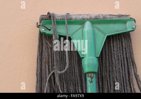 Vecchio mop giace contro una parete di colore rosa. Foto Stock