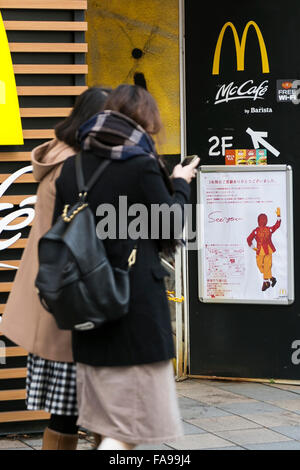 Tokyo, Giappone. 24 dicembre, 2015. I pedoni a piedi passato un poster che annuncia la chiusura del McDonald's più grande store in Giappone situato in Harajuku on gennaio 15, 2016. McDonald's secondo come riferito sta cercando di vendere il 15% al 33% di quote della sua filiale Giapponese e guadagno 100 miliardi di yen ($817 milioni di euro). McDonald's aziende Giappone è prevista una perdita netta di 38 miliardi di yen durante il suo anno fiscale conclusosi il 31 dicembre dopo gli scandali di scaduto il pollo nell'estate del 2014 e la contaminazione con corpi estranei nel gennaio 2015. © Rodrigo Reyes Marin/AFLO/Alamy Live News Foto Stock