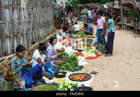 MYINKABA, Myanmar — i venditori locali espongono prodotti freschi e merci al mercato mattutino nel villaggio di Myinkaba, vicino a Bagan, Myanmar. Frutta colorata, verdura e cibi tradizionali si affiancano alle bancarelle improvvisate lungo la strada. Foto Stock