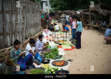 MYINKABA, Myanmar — i venditori locali espongono prodotti freschi e merci al mercato mattutino nel villaggio di Myinkaba, vicino a Bagan, Myanmar. Frutta colorata, verdura e cibi tradizionali si affiancano alle bancarelle improvvisate lungo la strada. Foto Stock