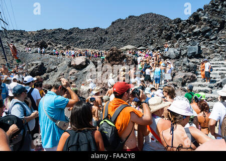 Santorini, Erinia Bay, Nea Kameni. I turisti a piedi al bordo del vulcano dal porto lungo ruvida percorso roccioso attraverso il paesaggio desolato sotto il sole caldo. Foto Stock