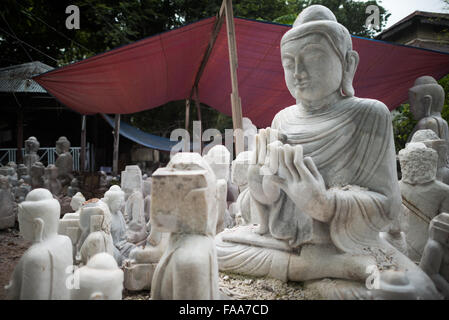 MANDALAY, Myanmar - gli artigiani locali intraprendono il lavoro polveroso e sfrenato di intagliare statue del Buddha in marmo. Poiché il buddismo è la religione dominante in Myanmar, c'è una notevole domanda di statue, con i clienti in grado di scegliere tra una miriade di pose, dimensioni e stili. Gli artigiani sono raggruppati in una strada nel quartiere Chanmyathazi di Mandalay vicino alla Pagoda Mahamuni. Foto Stock