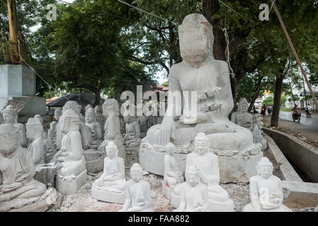 MANDALAY, Myanmar - gli artigiani locali intraprendono il lavoro polveroso e sfrenato di intagliare statue del Buddha in marmo. Poiché il buddismo è la religione dominante in Myanmar, c'è una notevole domanda di statue, con i clienti in grado di scegliere tra una miriade di pose, dimensioni e stili. Gli artigiani sono raggruppati in una strada nel quartiere Chanmyathazi di Mandalay vicino alla Pagoda Mahamuni. Foto Stock