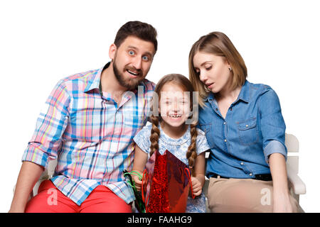 La famiglia felice con le borse della spesa seduta presso lo studio Foto Stock