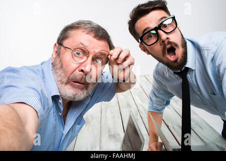 Due colleghi facendo le foto alla loro auto seduto in ufficio Foto Stock