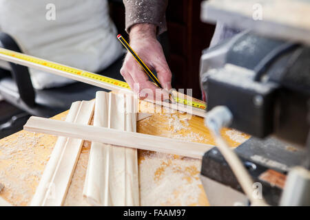 Carpenter lavora con i montanti delle porte. Egli è la misurazione di legno e la marcatura con matita Foto Stock