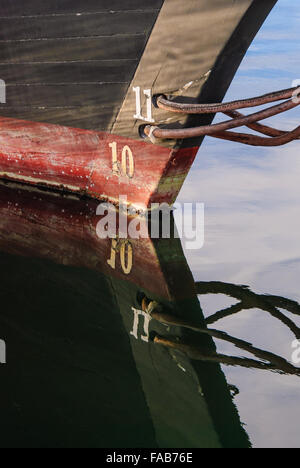 Close-up dettaglio di Goletta prora in corrispondenza della linea di galleggiamento con il riflesso speculare sulla superficie dell'acqua. Foto Stock