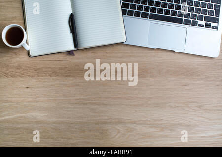 Laptop e Blocco note con penna e la tazza di caffè su una superficie di legno. Foto Stock