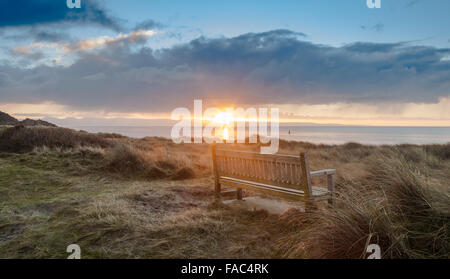 Panca in legno sulla riva erbosa, Alba Pwllheli Beach in Galles Foto Stock