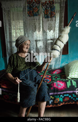 Donna anziana mentre la filatura della lana nel distretto di Maramures, Romania Foto Stock