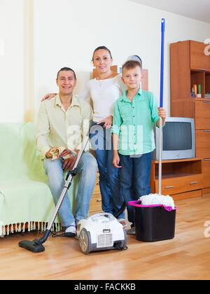 Stanco della famiglia di tre finito di pulire con aspirapolvere in casa Foto Stock