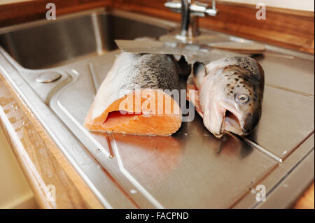 Salmone intero essendo preparato per la cottura al lavello da cucina Foto Stock