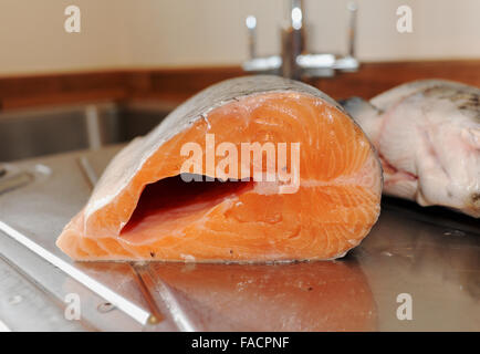 Salmone intero essendo preparato per la cottura al lavello da cucina Foto Stock