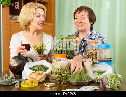 Due anziani vicini spendere il loro tempo libero a casa e di bere il tè alle erbe Foto Stock