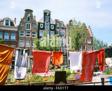 Le vecchie case a fianco di un canale di Amsterdam. Al primo piano l'asciugatura di biancheria in una casa galleggiante Foto Stock