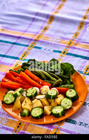 Siviera di vapore fresco raccolte verdure giovani compresi crinkle tagliare le carote affettate, piselli e manganelli di patate Foto Stock