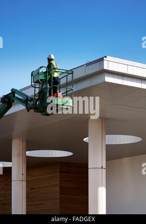 Operaio edile utilizza cherry picker per raggiungere il tetto di un edificio in costruzione a Huddersfield Leisure Centre copia spazio per il testo Foto Stock