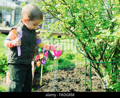 Little Boy lavora in giardino - impianti di irrigazione Foto Stock
