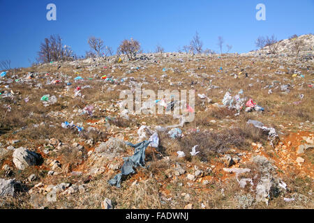 Plastica scartati shopping bags da un garbage incustodito impianto di smaltimento, prati di inquinanti sul pendio di una collina in Croazia. Foto Stock