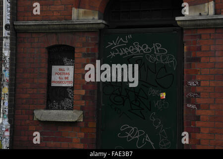 Graffiti scrawl porta da un lampione con adesivi, 'Bill manifesti saranno perseguiti a norma di legge di preavviso, Bedford House, Wheler Street, Londra Foto Stock