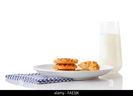 Pila di tre fatti in casa il burro di arachidi cookie e metà dei cookie sul piatto di portata in ceramica bianca su blu tovagliolo e bicchiere di latte Foto Stock