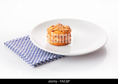 Pila di tre fatti in casa il burro di arachidi cookie sul piatto di portata in ceramica bianca sul tovagliolo blu, isolato su sfondo bianco Foto Stock