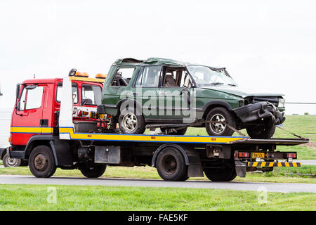 Gravemente danneggiata write-off verde auto, Range-Rover fissato sul carrello di recupero, dopo ribaltamento in incidente d'auto. Ore diurne. Foto Stock