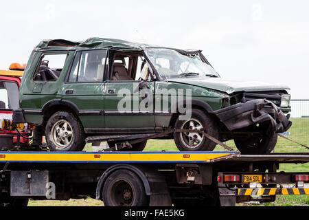 Gravemente danneggiata write-off verde auto, Range-Rover fissato sul carrello di recupero, dopo ribaltamento in incidente d'auto. Ore diurne. Foto Stock