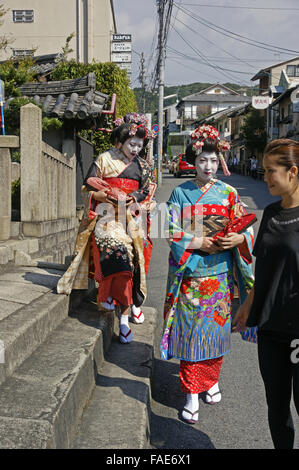 Femmina giapponesi turisti essendo guidato su strada vestito per una Maiko esperienza in Kyoto Foto Stock