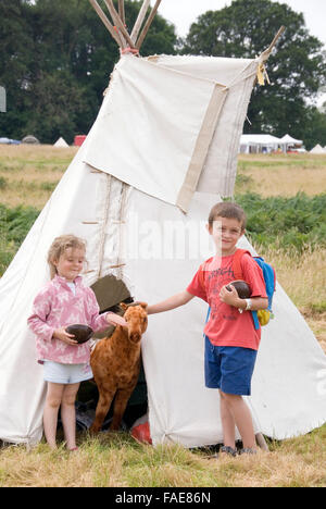 CHEPSTOW, GALLES - Luglio 2014: 2 giovani bambini pet a cavallo ripiene alla porta di un tende Tepee il 31 luglio presso la Raccolta verde Foto Stock