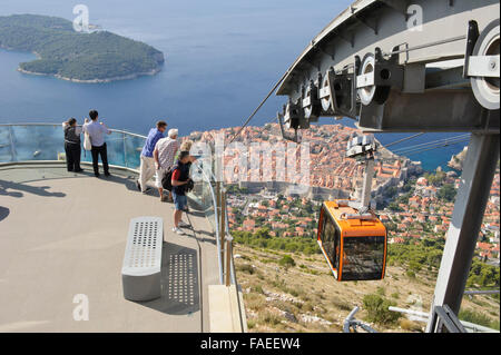 I turisti su una piattaforma di avvistamento sulla cima della collina con l'isola di Lokrum e una funivia, Dubrovnik, Croazia. Foto Stock