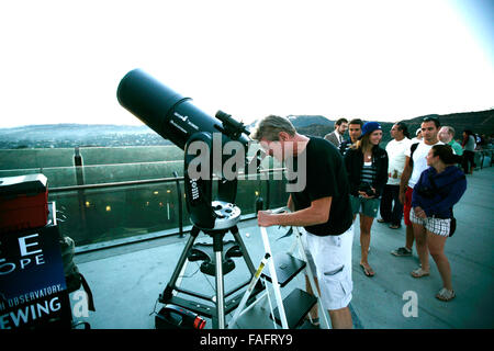 Uomo che guarda le stelle attraverso un telescopio di grandi dimensioni con la linea del popolo. Foto Stock