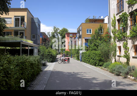 Ciclista (con carrozzina) nel verde sobborgo di Vauban, Freiburg, Germania. Foto Stock