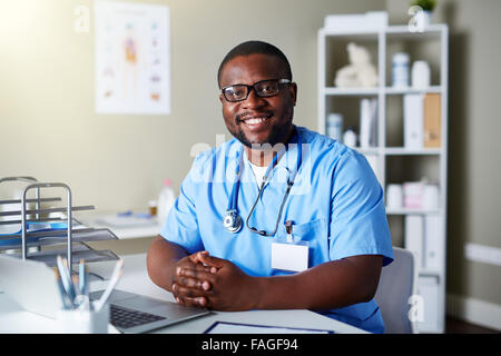 Giovane medico in uniforme seduti al posto di lavoro Foto Stock
