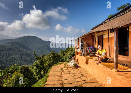 Uomo nepalese si siede di fronte a casa sua in Himalaya montagne Foto Stock