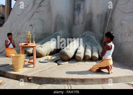 Un giovane sacerdote adorare ai piedi di Gommateshwara bahubali a Shravanabelagola nel distretto di Hassan di Karnataka, India Foto Stock