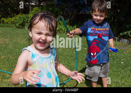 Little Boy il lavaggio la sua sorellina nel giardino. Foto Stock