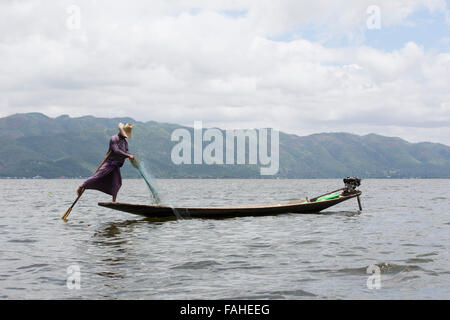 Un pescatore dal popolo Intha canottaggio la sua barca sul Lago Inle in Myanmar (Birmania). L'uomo è uno della gamba vogatori, chi può fila Foto Stock