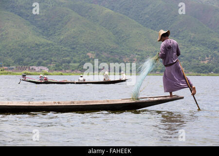 Un pescatore dal popolo Intha canottaggio la sua barca sul Lago Inle in Myanmar (Birmania). L'uomo è uno della gamba vogatori, chi può fila Foto Stock