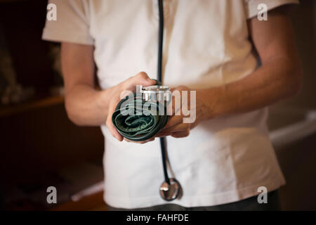 Medico tenendo un bracciale per la misurazione della pressione sanguigna e indossando uno stetoscopio Foto Stock