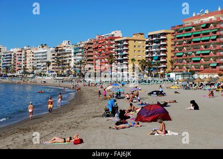 I villeggianti rilassante sulla spiaggia con alberghi e appartamenti per la parte posteriore, Fuengirola, provincia di Malaga, Andalusia, Spagna. Foto Stock