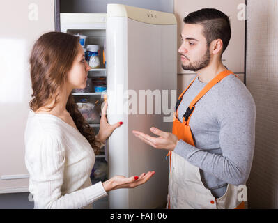 Giovane massaia mostrando rotture frigorifero a gravi repairman Foto Stock