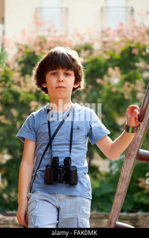 I giovani di osservazione degli uccelli un ragazzino di sette con un binocolo Foto Stock