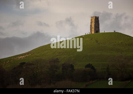 Glastonbury, Somerset, Regno Unito. Il 31 dicembre, 2015. Centinaia di persone che fanno il pellegrinaggio Vigilia di Capodanno al top di Glastonbury Tor nonostante i forti venti e minaccia di docce a pioggia. Molte più persone rimarranno sul fianco di una collina che si affaccia sulla pianura alluvionale del Somerset per vedere la prima alba del 2016. Credito: Wayne Farrell/Alamy Live News Foto Stock