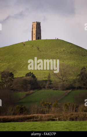 Glastonbury, Somerset, Regno Unito. Il 31 dicembre, 2015. Centinaia di persone che fanno il pellegrinaggio Vigilia di Capodanno al top di Glastonbury Tor nonostante i forti venti e minaccia di docce a pioggia. Molte più persone rimarranno sul fianco di una collina che si affaccia sulla pianura alluvionale del Somerset per vedere la prima alba del 2016. Credito: Wayne Farrell/Alamy Live News Foto Stock