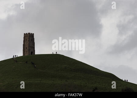 Glastonbury, Somerset, Regno Unito. Il 31 dicembre, 2015. Centinaia di persone che fanno il pellegrinaggio Vigilia di Capodanno al top di Glastonbury Tor nonostante i forti venti e minaccia di docce a pioggia. Molte più persone rimarranno sul fianco di una collina che si affaccia sulla pianura alluvionale del Somerset per vedere la prima alba del 2016. Credito: Wayne Farrell/Alamy Live News Foto Stock