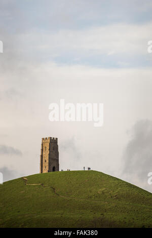 Glastonbury, Somerset, Regno Unito. Il 31 dicembre, 2015. Centinaia di persone che fanno il pellegrinaggio Vigilia di Capodanno al top di Glastonbury Tor nonostante i forti venti e minaccia di docce a pioggia. Molte più persone rimarranno sul fianco di una collina che si affaccia sulla pianura alluvionale del Somerset per vedere la prima alba del 2016. Credito: Wayne Farrell/Alamy Live News Foto Stock