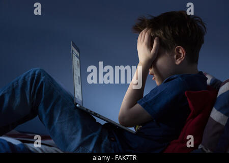 Online cyber bullismo Bullismo foto di un ragazzo sconvolto nella sua camera da letto guardando doloroso messaggi sui social media Foto Stock