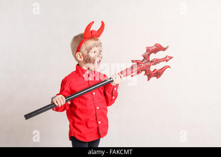 bambino divertente in costume halloween diavolo con corna e tridente su un  ragazzo di sfondo di legno scuro con trucco nero per halloween, zombie Foto  stock - Alamy